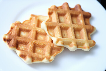 Two freshly baked Belgian waffles on white plate