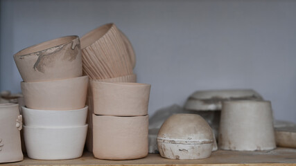 Handmade ceramic crockery on wooden shelf in creative studio