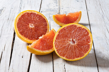 Fresh grapefruit slices on white wooden table