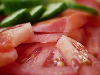 Large red delicious tomatoes and fresh cucumbers sliced for salad. Vitamin food for vegetarians,...