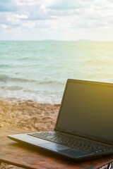 freelancer workplace on the sandy beach with a computer on the table. against the backdrop of the ocean and blue sky