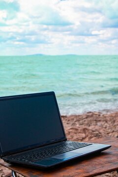 freelancer workplace on the sandy beach with a computer on the table. against the backdrop of the ocean and blue sky © Torkhov