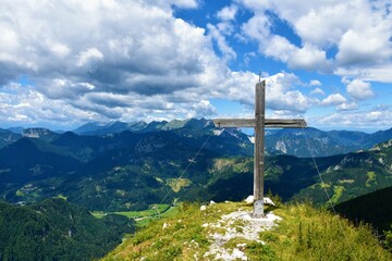 View of range in Karavanke mountains in Gorenjska, Slovenia with mountains Kosutnikov Turn and Kladivo and a wooden cross at the top of Goli Vrh mountain above Jezersko with clouds in the sky