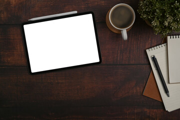 Digital tablet, coffee cup, notebook and potted plant on wooden office desk