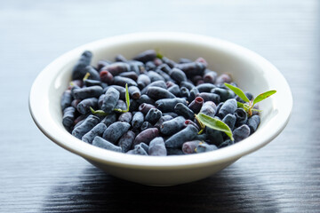 Fresh honeysuckle in white plate over wooden table