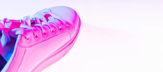 Closeup female sports shoes, sneakers isolated over neoned background. Urban city fashion, fitness, sport, training concept.