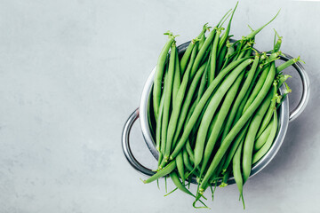 Green beans. Fresh raw organic Green beans in colander on gray stone background, top view