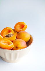 Fresh ripe apricots in a bowl on white background.