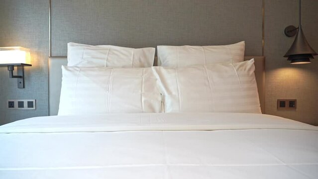 Pan across a hotel bed with stacked pillows.