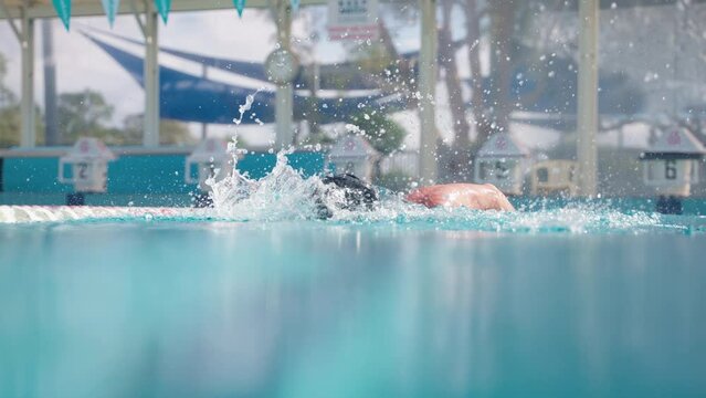 Slow Motion Close Up On Water Surface Of Professional Freestyle Swimmer In Cap Doing Laps In Outdoor Pool