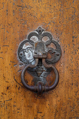 Closeup view of weathered antique bronze door knocker on beautiful ancient wooden door, Montpellier, France