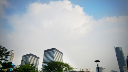 The view of a clear blue sky, with beautiful white clouds, surrounds the tall building.