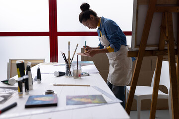 Image of biracial female artist working on new painting in studio