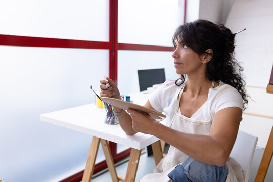 Image of biracial female artist working on new painting in studio