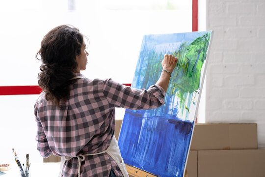 Image of biracial female artist working on new painting in studio