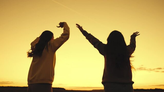 happy girls jump with raised hands sunset. success joy achieving teamwork. silhouette winners competition. girls with long hair against sky. beach party dancing evening. concept friendly team success.