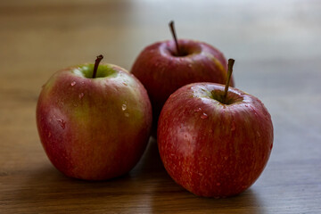 Apples on the table. Close-up of three red apples. The friut is ripe and ready to eat. 