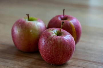 Apples on the table. Close-up of three red apples. The friut is ripe and ready to eat. 