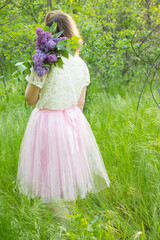 girl in forest with lilac bouquet in pink skirt