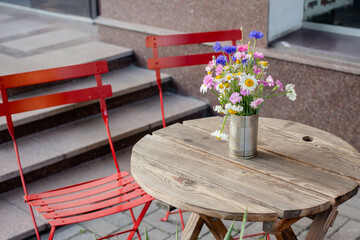 cafe table with flowers. wooden table with colorful chair. outside terrace.