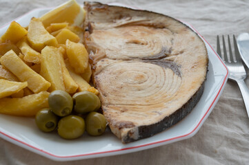 Seafood dish, grilled steak from swordfish or spada served with french fried potatoes and green olives
