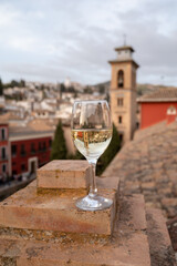 Glass of Spanish dry rueda white wine served on roof terrace with view on old part of Andalusian town Granada, Spain