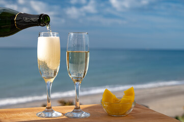Outdoor breakfast with Spanish cava sparkling wine and pineapple with view on blue sea and sandy...