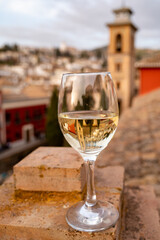 Glass of Spanish dry rueda white wine served on roof terrace with view on old part of Andalusian town Granada, Spain
