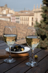 Two glasses of Spanish dry rueda white wine served with olives on roof terrace with view on old part of Andalusian town Granada, Spain