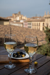 Two glasses of Spanish dry rueda white wine served with olives on roof terrace with view on old part of Andalusian town Granada, Spain
