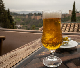 Spanish beer and glass bowl with green andalusian olives served on outdoor terrace with view on Sierra Nevada mountains in Granada, Andalusia, Spain