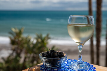 Spanish dry rueda white wine and black olives tapas served on beach terrace with view on...