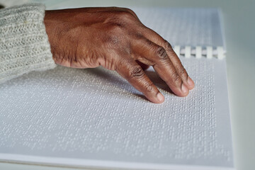 Close-up of African blind man reading with his right hand braille book at table