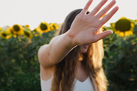 Eine Frau in einem Sonnenblumenfeld mit Stopp Geste