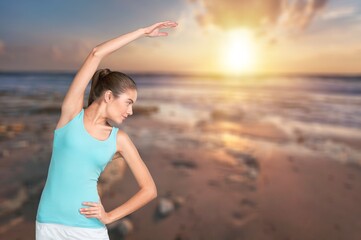 Satisfied fitness slim woman doing exercises by the sea. Healthy habits and lifestyle