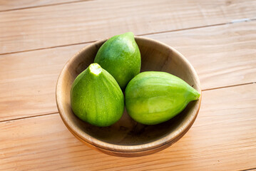 Ripe green figs in a wooden bowl on a table
