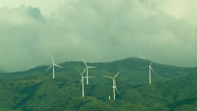 A commercial plane speeds thru the famous Nabas windmills covered by a cloudy day.