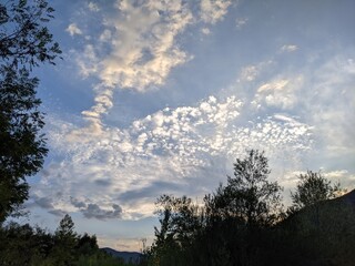 Obraz premium Beautiful cloudy sky at sunset over the river. The high bank of the river is overgrown with grass.