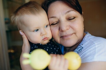 Fototapeta premium little caucasian baby girl and grandmother. woman hugging granddaugher with love
