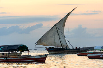 Fototapeta na wymiar traditional sailing dhow heading out to sea at dusk on a calm evening ocean