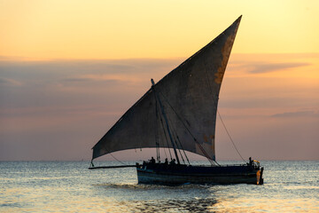 Fototapeta premium traditional sailing dhow heading out to sea at dusk on a calm evening ocean