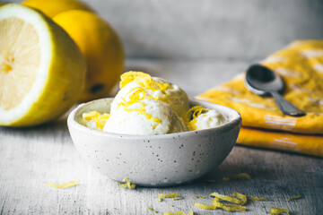 cuenco con helado de limón sobre una mesa de madera blanca, con limones detrás