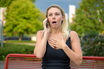 Woman reacting in shock and horror while using her mobile
