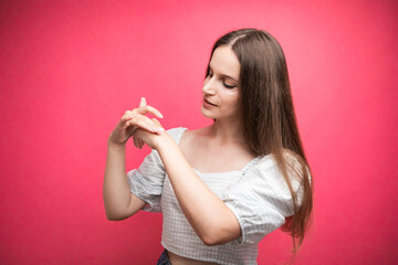 Naklejka premium Young woman applying hand cream on pink background