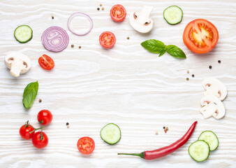 Food cooking background: arranged fresh ingredients, basil, cherry tomatoes, mushrooms, cut cucumber, onion, chilli pepper, spices on white wooden background top view, space for text