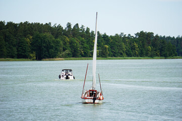 Sailboat swimming on a lake, shore with trees