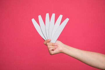Set of nail files in woman hand on pink background. Manicurist equipment