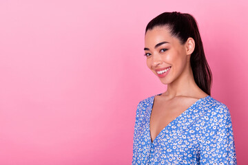 Photo of optimistic brunette lady near empty space wear blue blouse isolated on pink color background