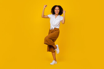 Full size portrait of overjoyed delighted person raise fists achievement isolated on yellow color background