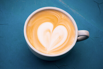 Cup of cappuccino on a blue table. Close up